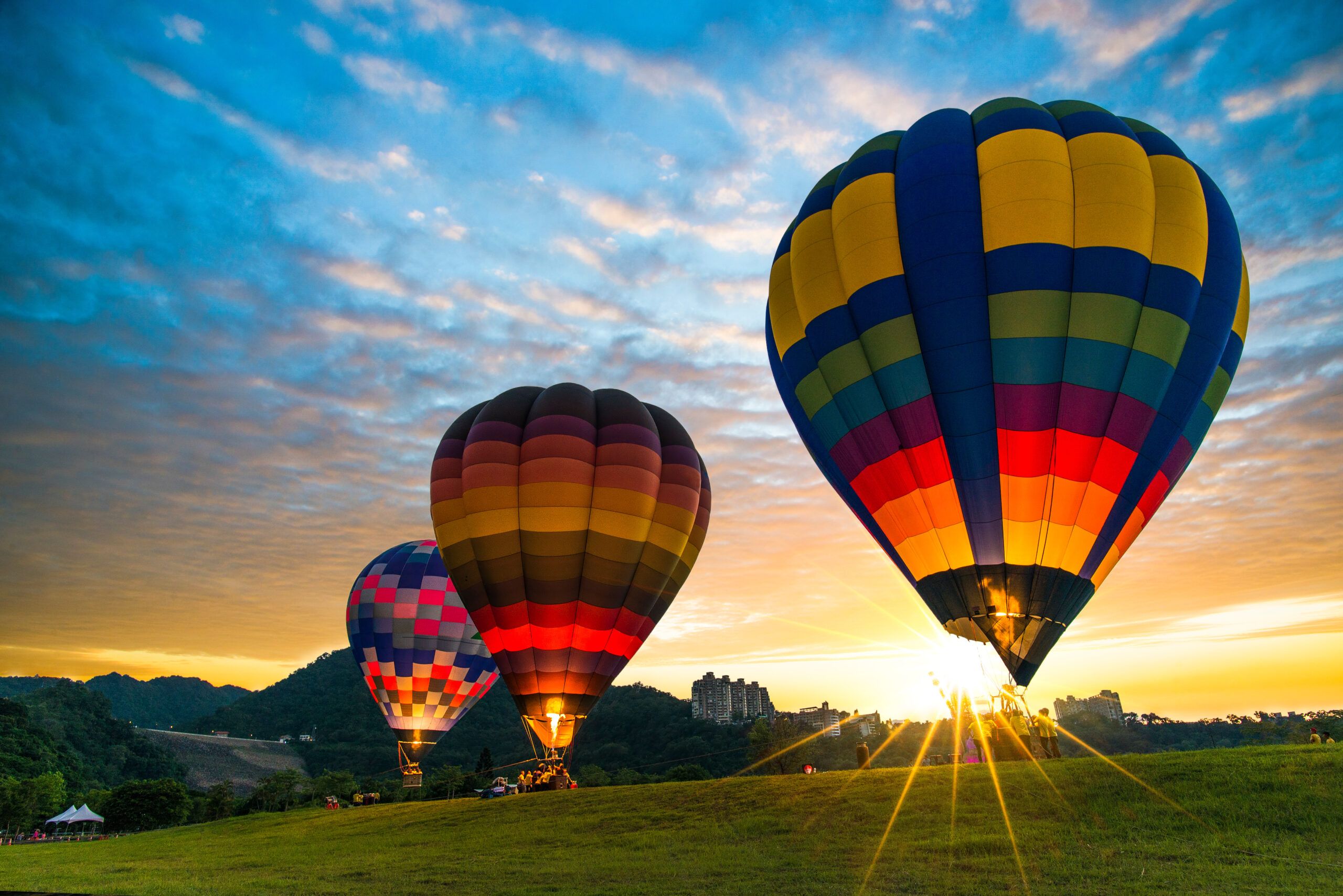 Hot air balloons floating above the ground in a field.