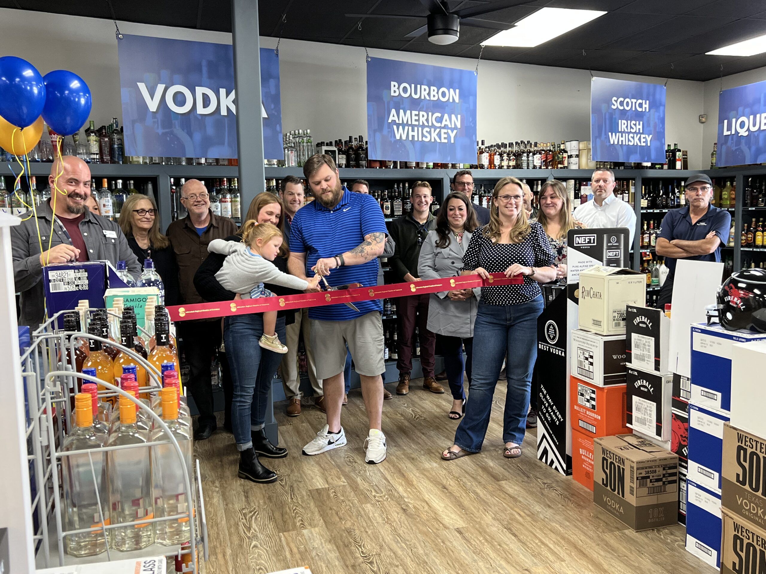 Queensbury Wine & Spirits owner Brian Miller cuts a ribbon to mark the store's opening.