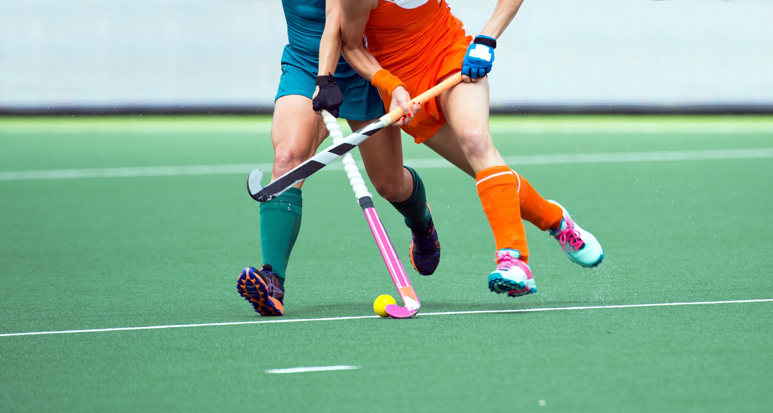 Two field hockey players battle for possession of the ball.