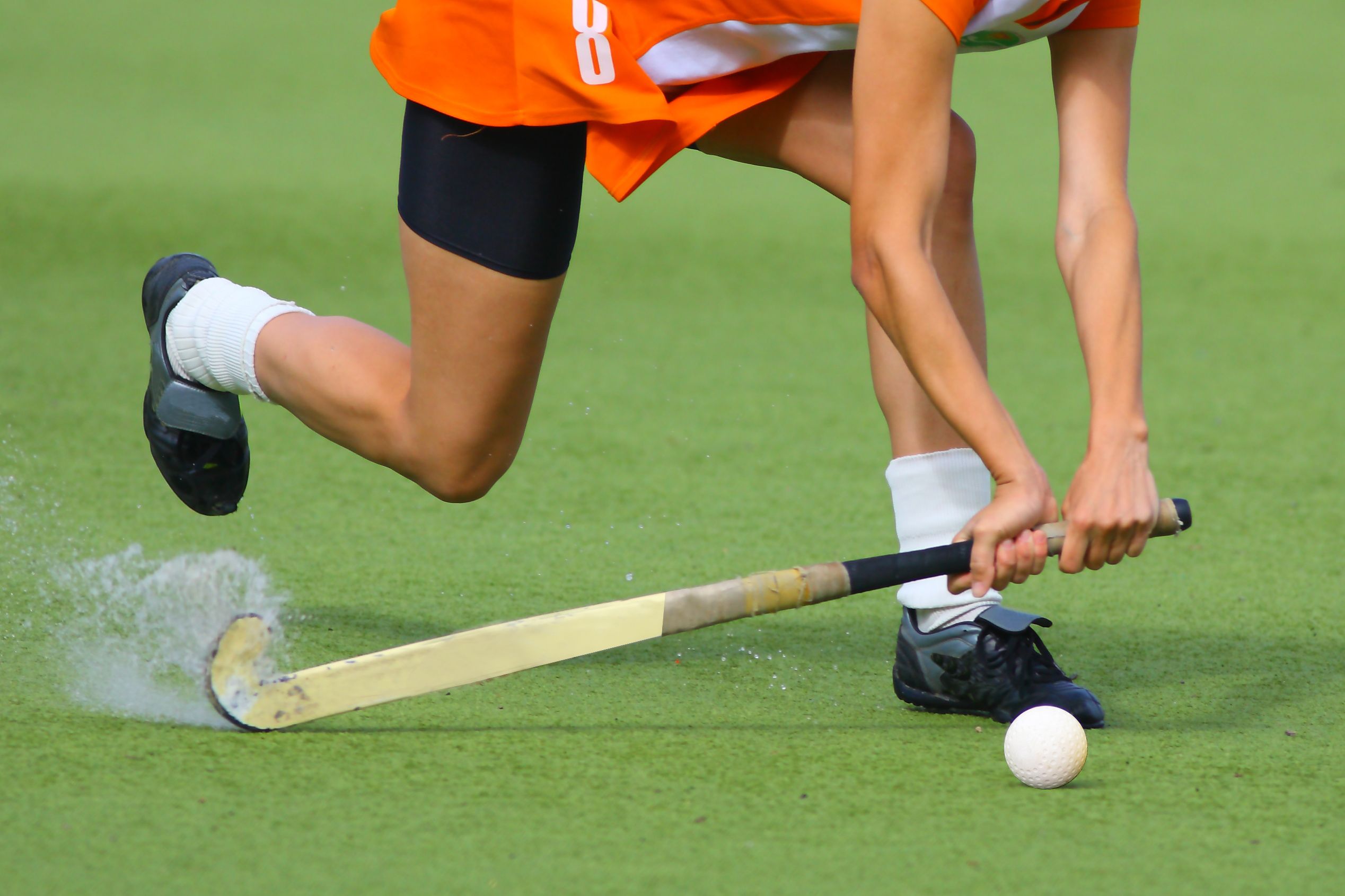 A field hockey player connects with the ball during a game.