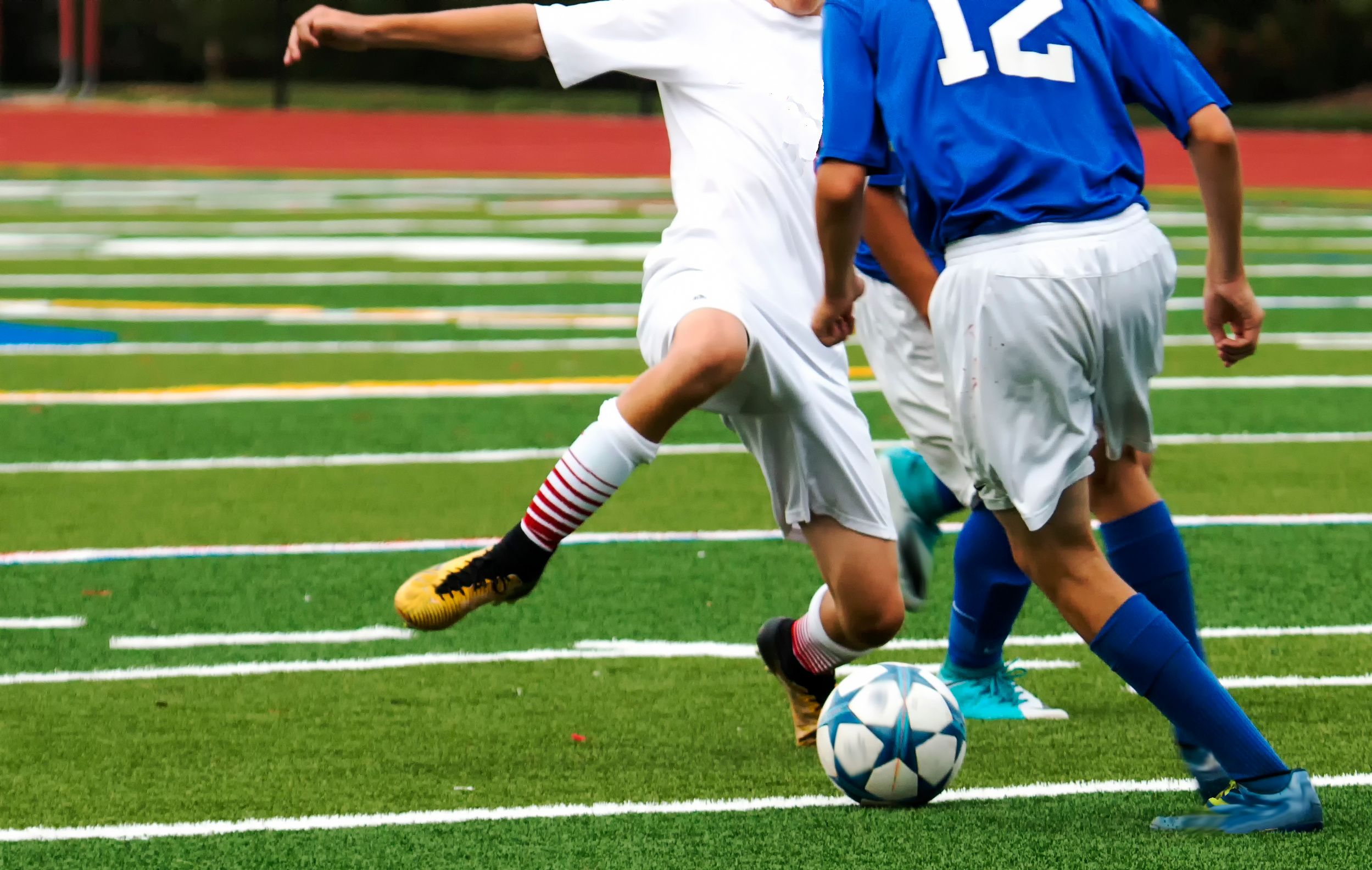 Two players battle for possession of a soccer ball during a game.