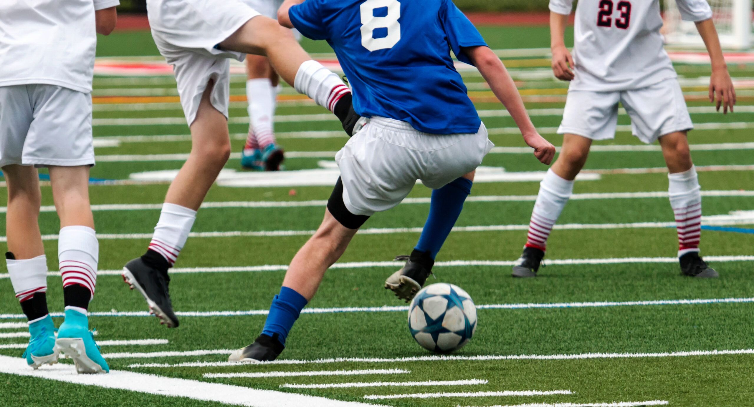 A soccer player dribbles around defenders.