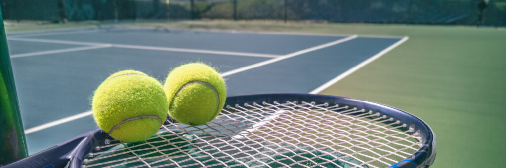 Tennis court panorama background with blue racket and two tennis balls ready to play match on outdoor courts summer sport lifestyle. Mobile photo picture.